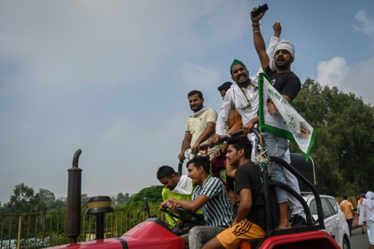 Farmers shout slogans as they climb atop a tractor during the protest in Muzaffarnagar