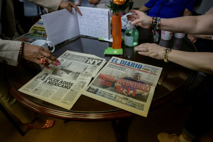 Hispanic cleaners from Ground Zero look at old newspapers that reported the death of Rafael Hernandez, an undocumented Mexican ex-firefighter who co-founded the support group Fronteras de Esperanza