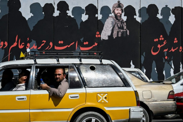 A man looks out of a car window as commuters make their way along a road in Kabul