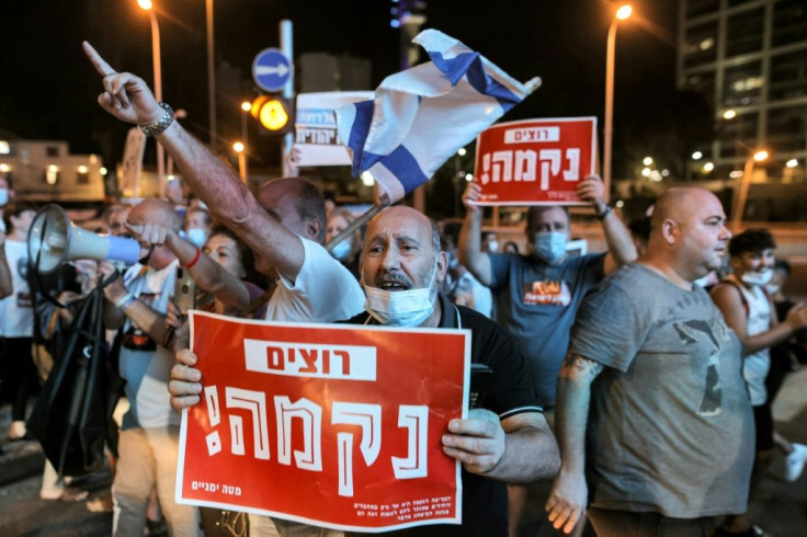 A protester in Tel Aviv holds a sign calling for "revenge" after the death of an Israeli border guard at the Gaza border