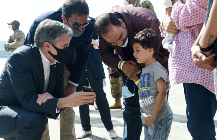 US Secretary of State Antony Blinken shows a picture of his children to a young Afghan refugee during evacuation operations at Ramstein Air Base in Germany