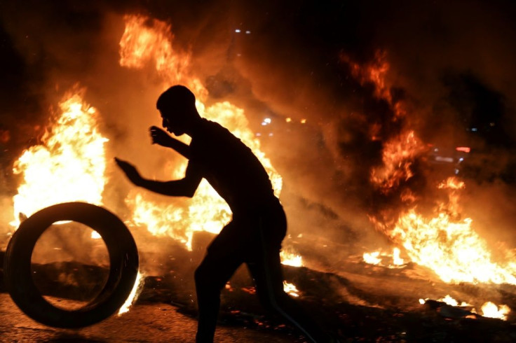 A youth prepares to set a tyre ablaze during confrontations with Israeli security forces in Nablus after a rally in support of the Palestinian escapees
