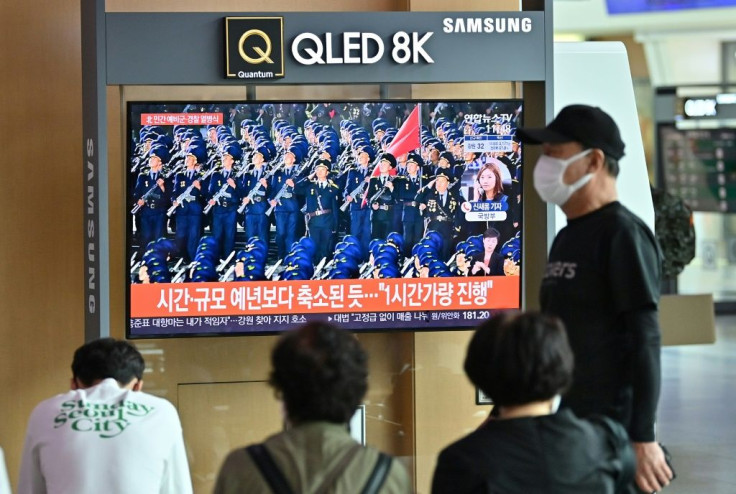 People in Seoul watch a news program reporting on the latest parade in North Korea