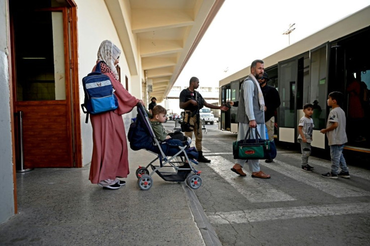 A Qatari security personnel (C) stands guard as passengers including a family bound for Germany board a shuttle bus before boarding a Qatar Airways aircraft at the airport in Kabul on September 9, 2021