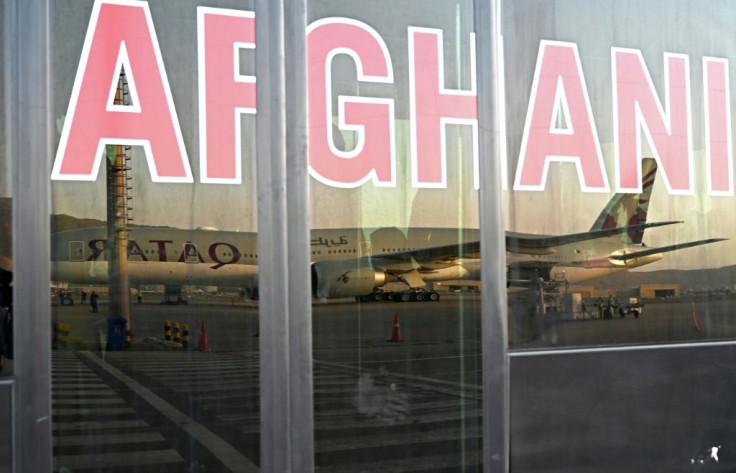 A Qatar Airways aircraft is reflected on the windowpanes of a shuttle bus carrying passengers to board the flight at the airport in Kabul on September 9, 2021