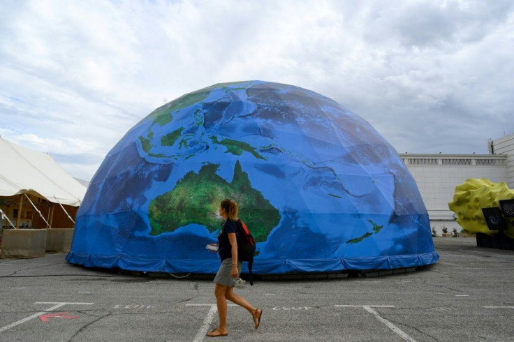A woman walks past a partial replica of the Earth during the IUCN congress in Marseille, southern France