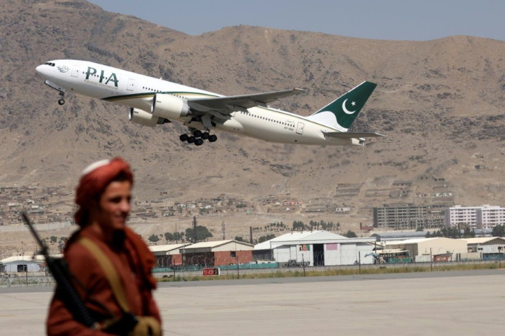 A Taliban fighter stands guard as a Pakistan International Airlines plane takes off from Kabul