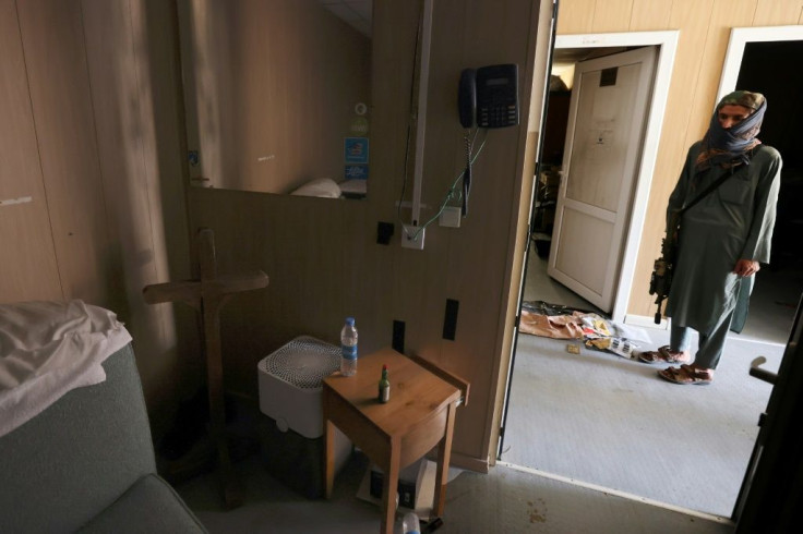 A Taliban fighter inspects a room with a cross and a bottle of Tabasco hot sauce at Kabul airport