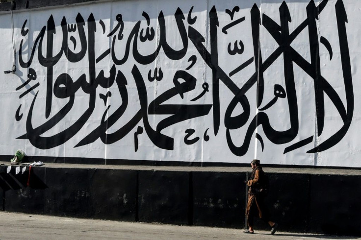 A man walks past a wall mural depicting the Taliban flag in Kabul