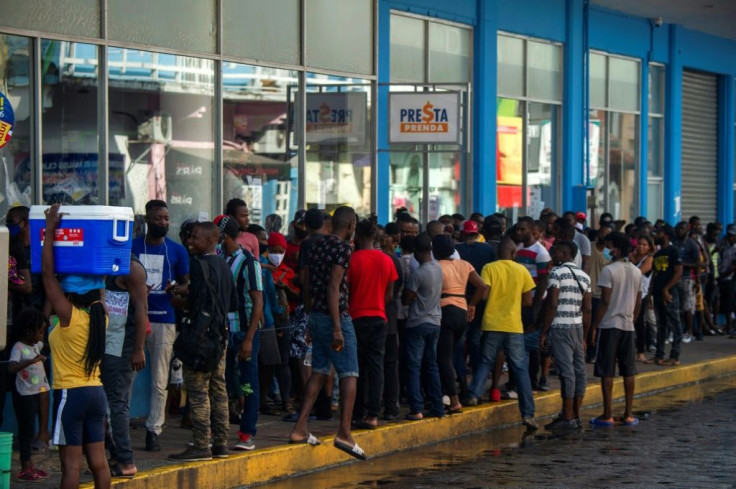 Migrants queue outside banks to collect money sent by relatives in the city of Tapachula in southern Mexico