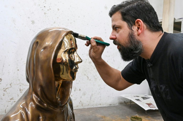 Sculptor Tamas Gilly applies a wax coating to the statue of Satoshi Nakamoto, bitcoin's mysterious inventor