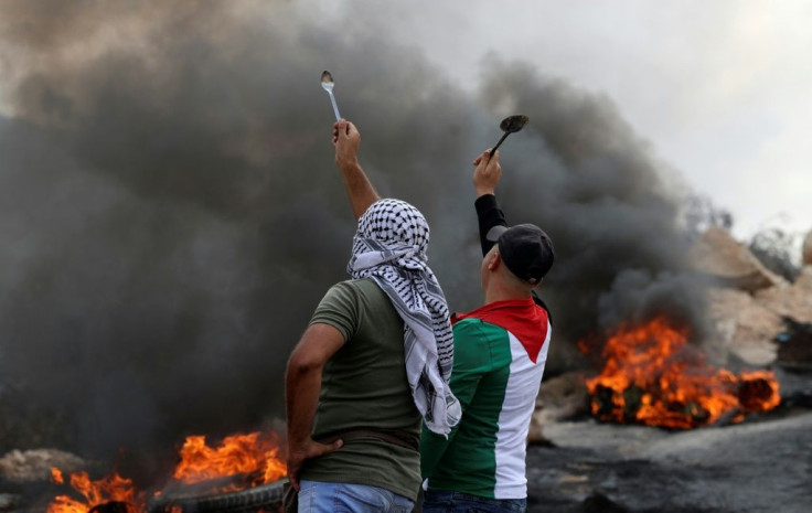 Palestinian protesters hold up spoons as they confront Israeli security forces in the West Bank village of Beita, on September 10, 2021
