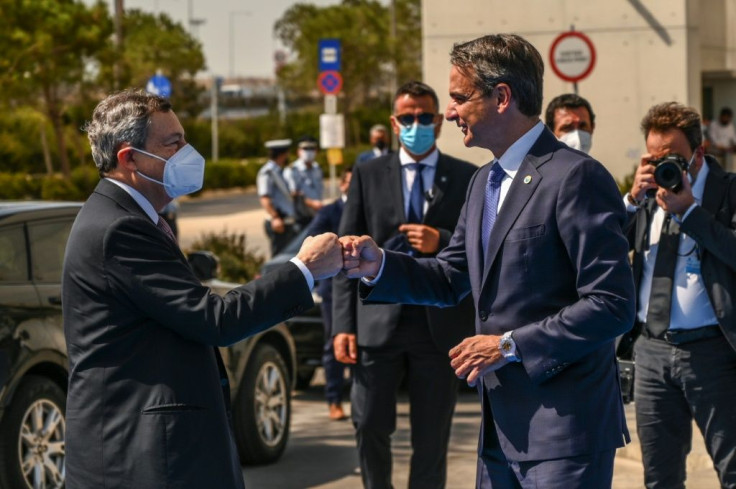 Greek Prime Minister Kyriakos Mitsotakis and Italy's Prime Minister Mario Draghi, masked, share a fist-bump greeting ahead of the outhern European summit in Athens