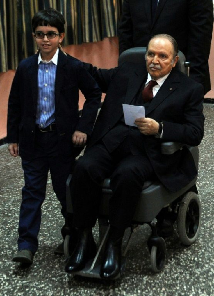 Abdelaziz Bouteflika is pushed in a wheelchair next to his nephew before casting his ballot at a polling station in Algiers while running for re-election on April 17, 2014
