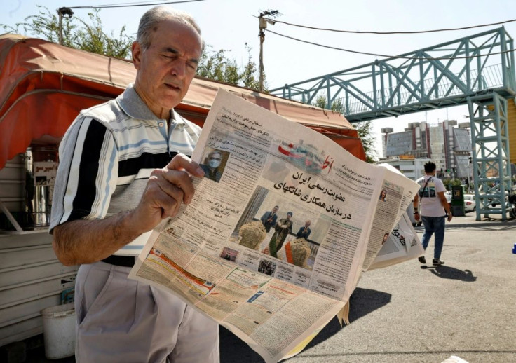 An Iranian man reads a copy of the daily newspaper "Etalaat" headlined, "Iran is a new member of the Shanghai Cooperation Organisation", at a kiosk in Tehran on September 18, 2021
