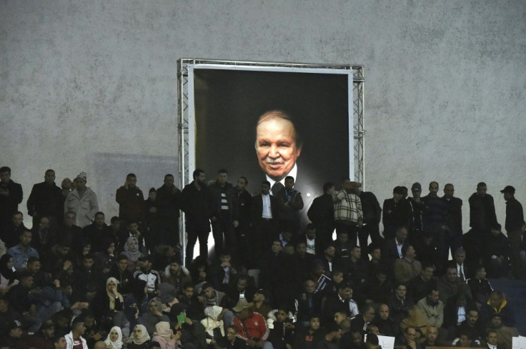 Supporters of Algeria's National Liberation Front (FLN) party gather on February 9, 2019 in the capital Algiers to call upon President Abdelaziz Bouteflika (shown in a poster) to run for a fifth term -- his decision to stand sparked mass protests