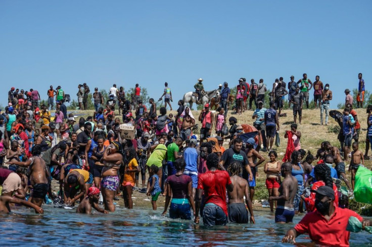 Haitian migrants, part of a group of over 10,000 people staying in an encampment on the US side of the border at Del Rio, Texas, cross the Rio Grande river to get food and water in Mexico.