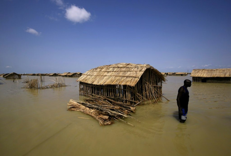 A South Sudanese refugee tries to repair his hut in flooded waters from the White Nile at a refugee camp which was inundated after heavy rain near in al-Qanaa, on September 14, 2021