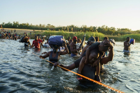 Migrants cross the Rio Grande river near the US-Mexico border on September 20, 2021