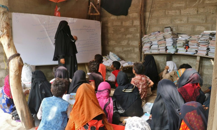 Yemeni teacher Amina Mahdi gives a lesson to children sprawled across the ground at her home in the rural area of Muhib in the southern province of Hodeida