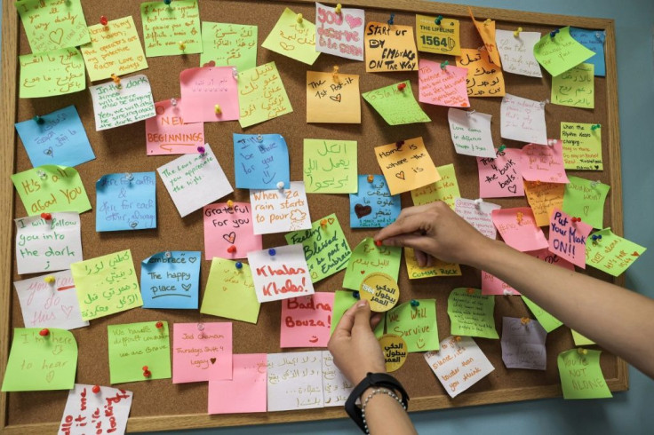 A woman places a note on a post-it board at the offices of Embrace, which says it receives around 1,100 calls a month