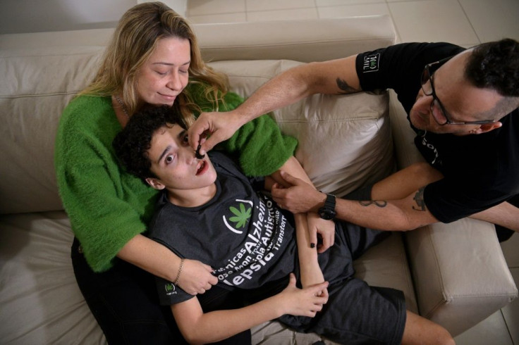 Gabriel Guerra (C) is held by his mother, Vanessa Opitz, while his father Ricardo Guerra gives him medicinal cannabis in Rio de Janeiro, Brazil in September 2021