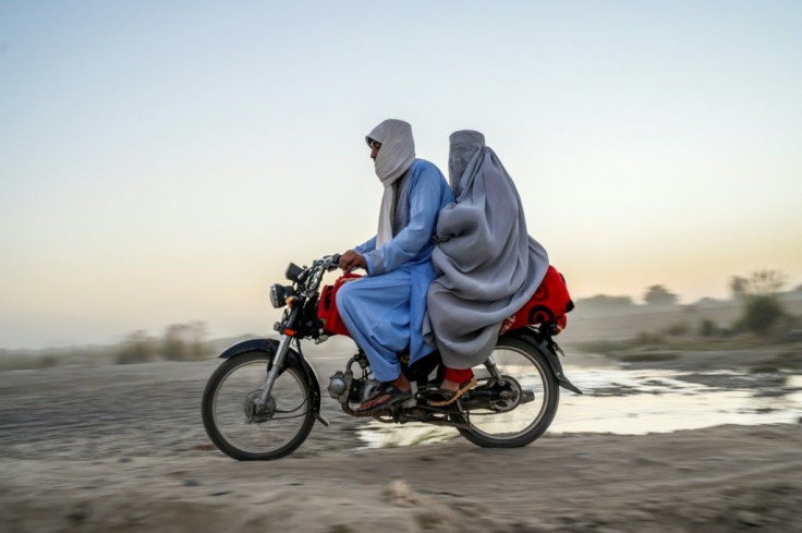 A woman wearing a burqa rides on the back of a mortorbike in Kandahar