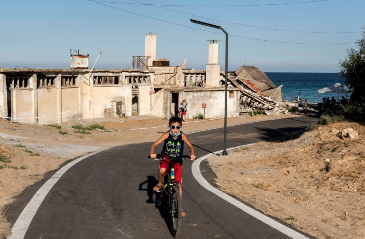 A child rides a bicycle on a street lined with derelict buildings in the fenced-off area of Varosha in northern Cyprus in June 2019 ahead of Turkish-backed plans to reopen the resort