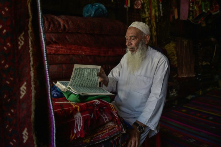An elderly carpet vendor reads from the holy Quran at his shop in Chicken Street in Kabul