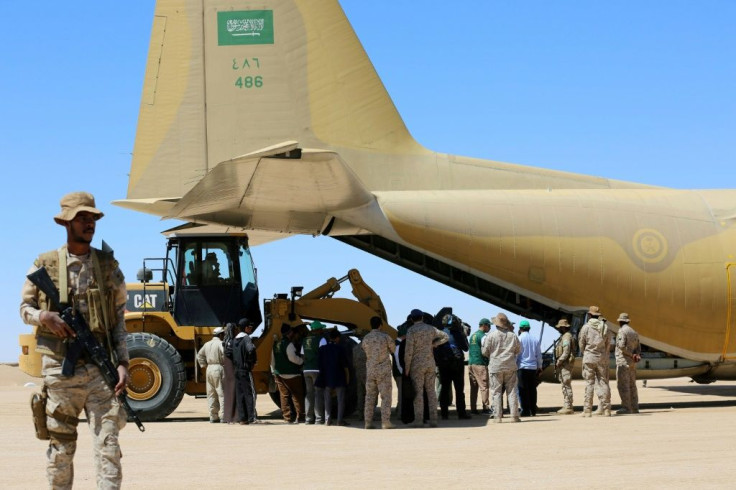 A picture taken on February 8, 2018 shows Saudi soldiers standing guard as workers unload aid from a Saudi air force cargo plane at an airfield in Yemen's central province of Marib