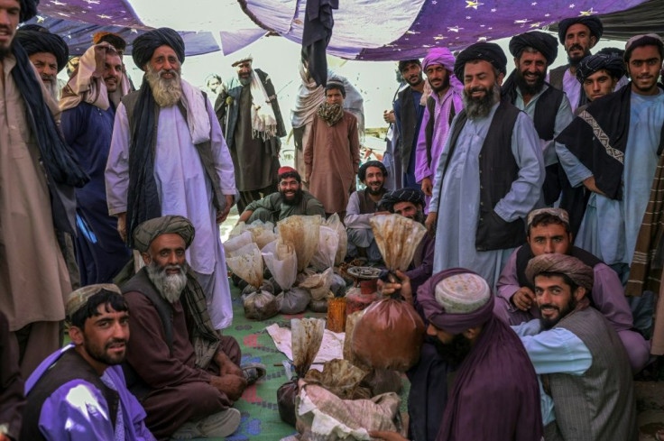 Opium vendors and buyers chat over green tea around sacks of opium and hashish