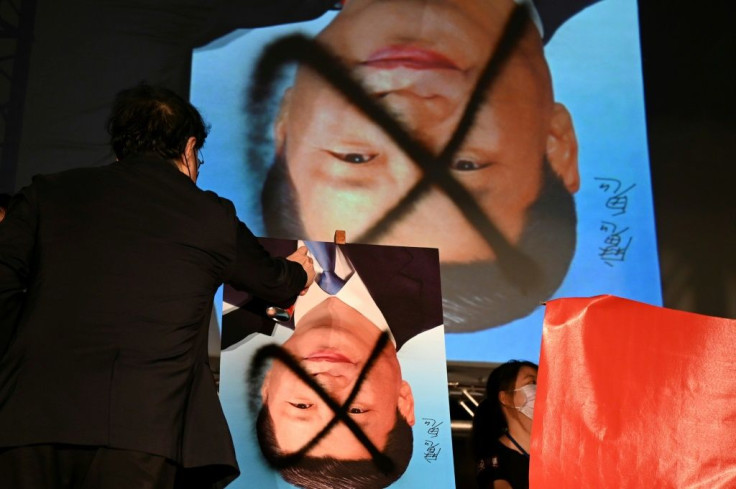 A demonstrator spray paints over a portrait of Chinese leader Xi Jinping during an anti-China rally outside the parliament in Taipei