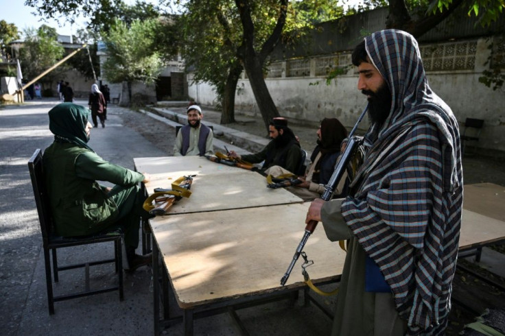 Taliban fighters sit outside the passport office after its reopening for applications in Kabul