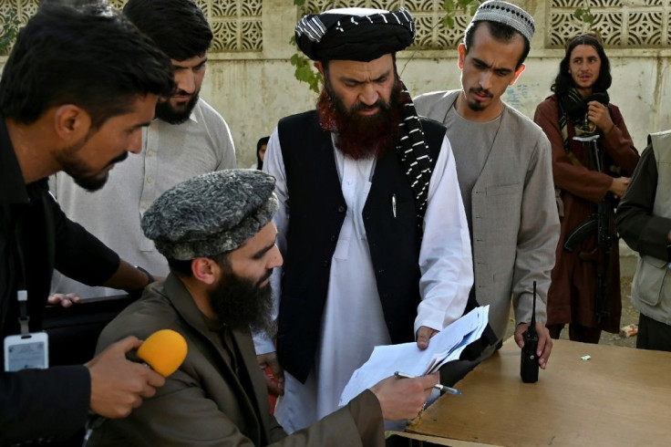 Mualvi Alam Gull Haqqani (C), head of the passport office, checks documents after the Taliban announced its reopening