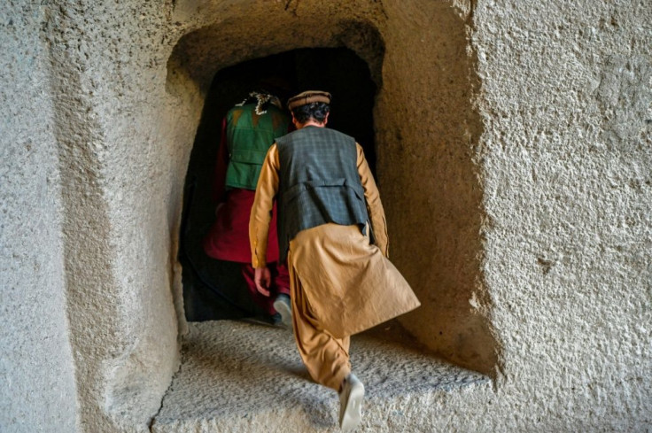 Members of Taliban walk at the site where the Shahmama Buddha statue once stood before being destroyed by the Taliban
