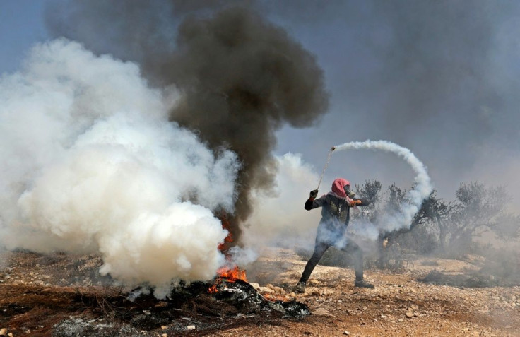 A Palestinian protester uses a slingshot to return a tear gas canister toward Israeli security forces during clashes following a demonstration against settlements in the village of Beita in the occupied West Bank, on October 8