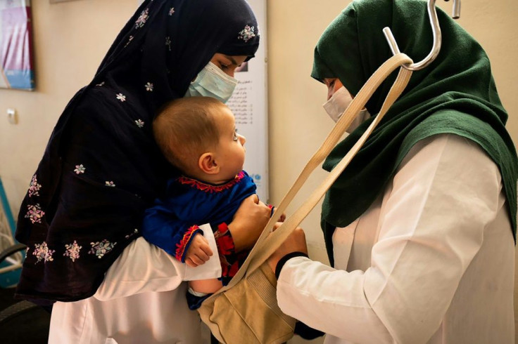 A midwife and a nutrition counsellor weigh a baby at the Tangi Saidan clinic