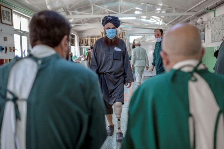 Mullah Yacoub (C), a Taliban member who claims to have lost his leg in an US strike, walks to try on his new prosthetic leg