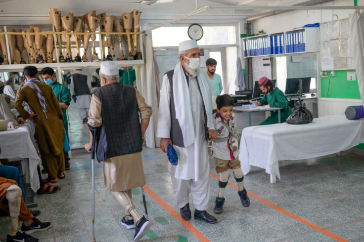 A child walks with his new prosthetic legs assisted by a relative at an International Committee of Red Cross Rehabilitation Centre in Kabul