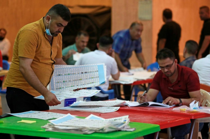 Employees of Iraq's Independent High Electoral Commission conduct a manual count of votes following the parliamentary elections in Baghdad's Green Zone area on October 13, 2021