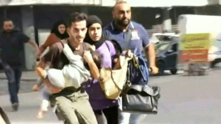 IMAGES A family runs holding their child as they flee the Tayouneh neighbourhood of Beirut during intensive gunfire clashes that broke out following a Beirut rally organised by the Shiite Hezbollah and Amal movements to demand the dismissal of the lead i