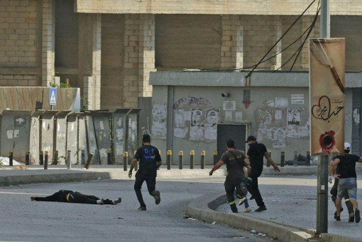Fighters from the Shiite Hezbollah and Amal movements rush to the body of a fallen comrade during clashes in Beirut's Tayouneh area