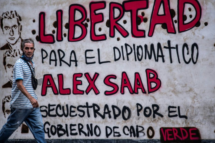 A man walks past graffiti reading "Freedom for diplomat Alex Saab, kidnapped by the government of Cape Verde" in Caracas, Venezuela