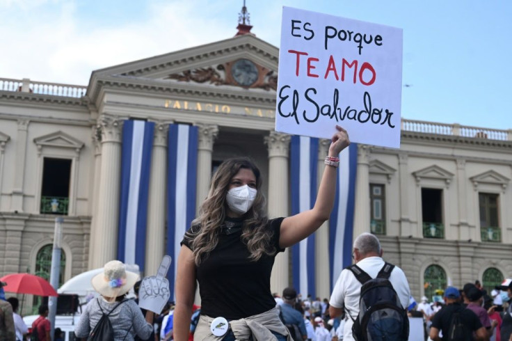 A woman holds a poster that reads, "It's because I love you El Salvador" during a demonstration against bitcoin and other economic measures, as well as a decree that removed judges from their functions, in San Salvador October 17, 2021