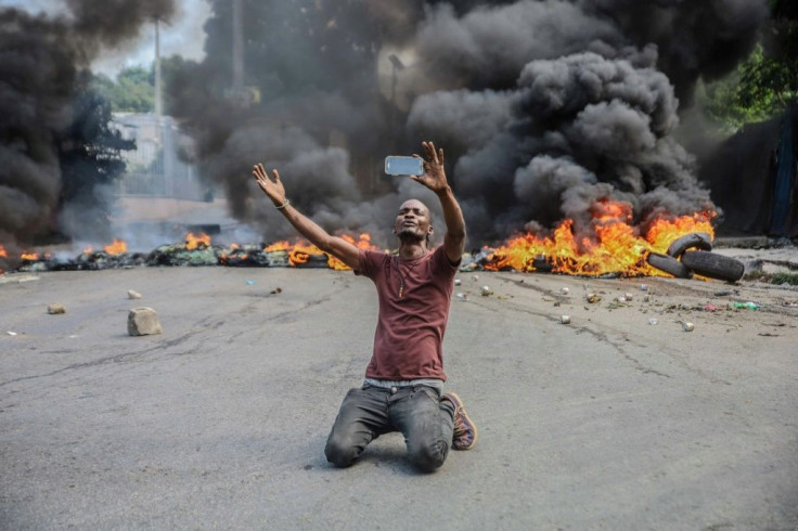 A man films himself in front of burning tires during a general strike   to denounce insecurity in Haiti's capital Port-au-Prince on October 18, 2021