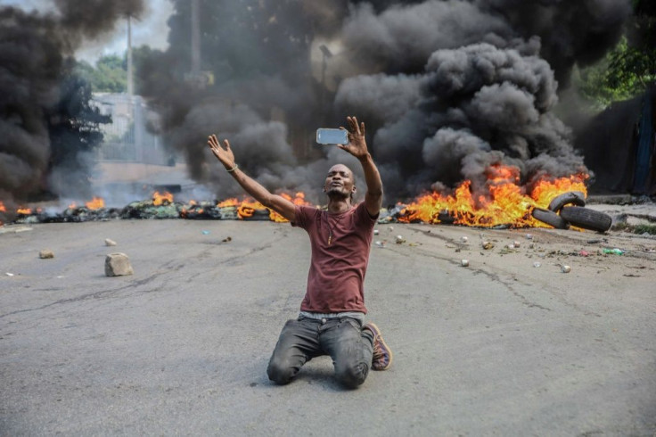 A man films himself in front of burning tires during a general strike to denounce insecurity in Haiti's capital Port-au-Prince on October 18, 2021