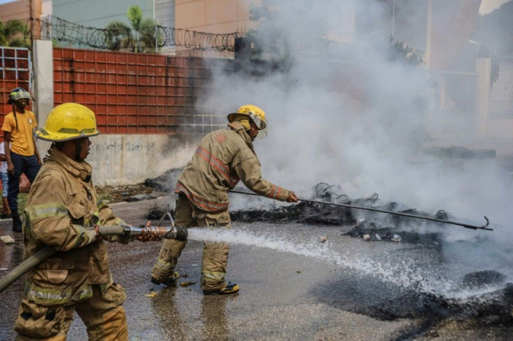 Firefighters extinguish the flames of burning tires during a general strike in Port-au-Prince, Haiti, to denounce the insecurity after the kidnappings of North American missionaries