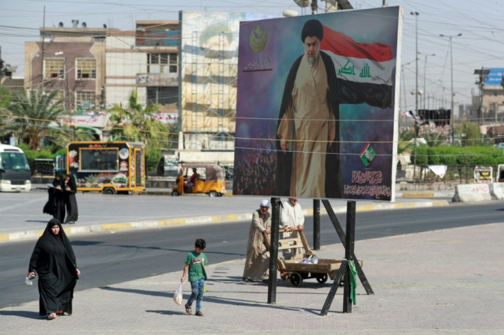 Iraqis pass by a poster of Shiite cleric Muqtada al-Sadr in Sadr City in Baghdad on October 17, 2021