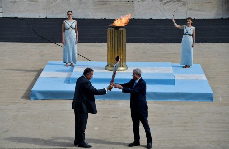 Yu Zaiqing (R) receives the torch with the Olympic flame from president of the Hellenic Olympic Committee Spyros Capralos