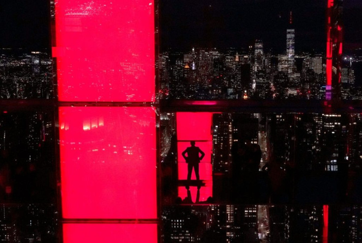 Influencer Rachel Wasley poses in a window with the Empire State building in the distance (R) during a press preview ahead of the grand opening of SUMMIT One Vanderbilt in New York, October 18, 2021